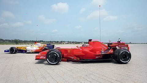 F1 car models against the backdrop of villages along the Yamuna Expressway.