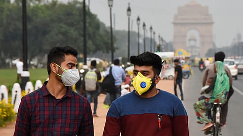 People wearing face masks on a Delhi road close to India Gate as a preventive measure against the spread of the Coronavirus outbreak.