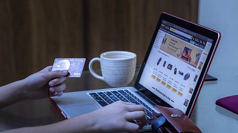 A representational image of a shopper using their card to shop for products on an e-commerce website.