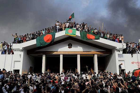 Anti-government protestors display Bangladesh's national flag as they storm Prime Minister Sheikh Hasina's palace in Dhaka on August 5, 2024. 