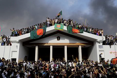 Anti-government protestors display Bangladesh's national flag as they storm Prime Minister Sheikh Hasina's palace in Dhaka on August 5, 2024.